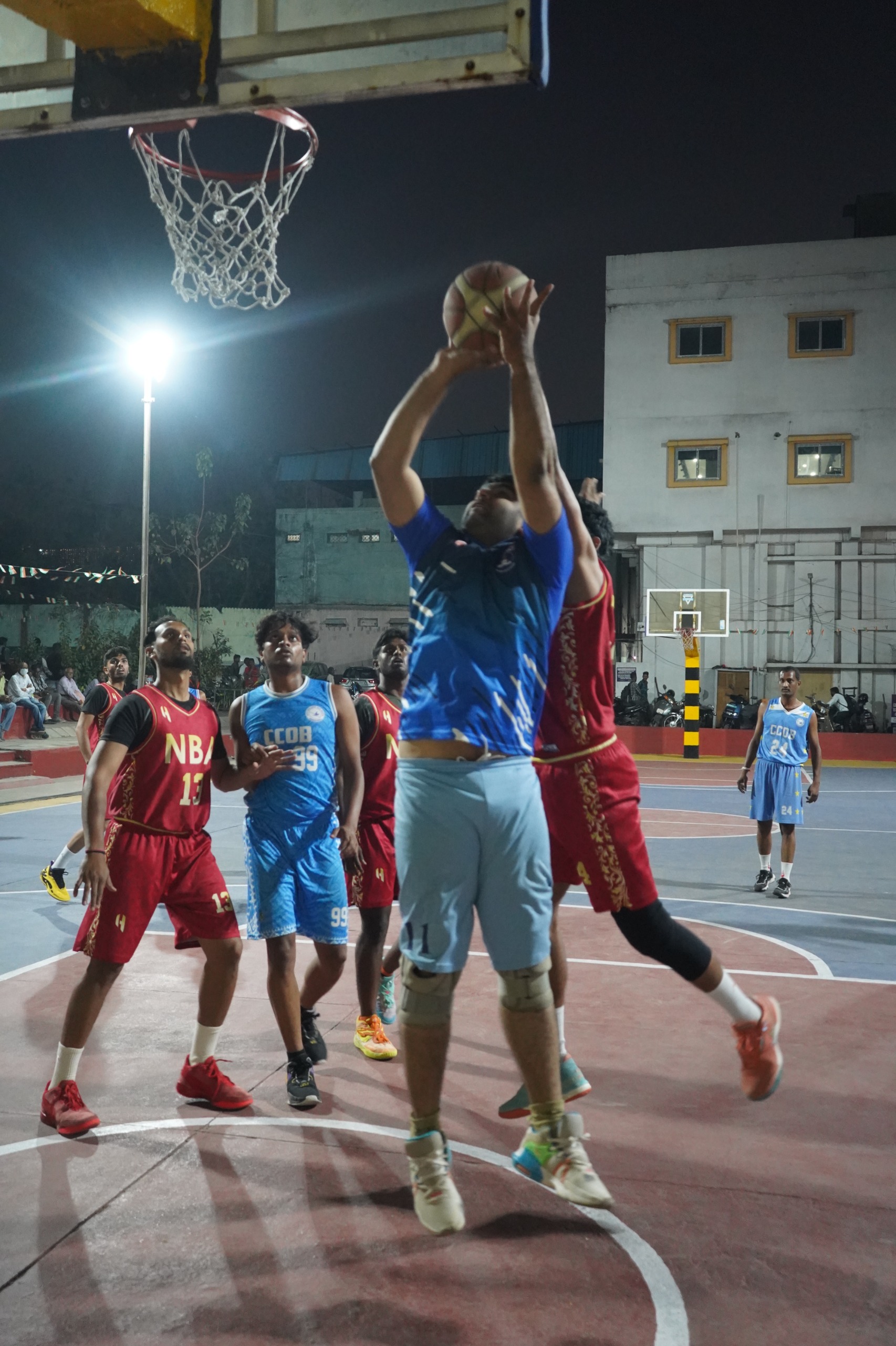 Saleem (Blue) of CCOB scoring from an offensive rebound against Nizam Basketball Academy