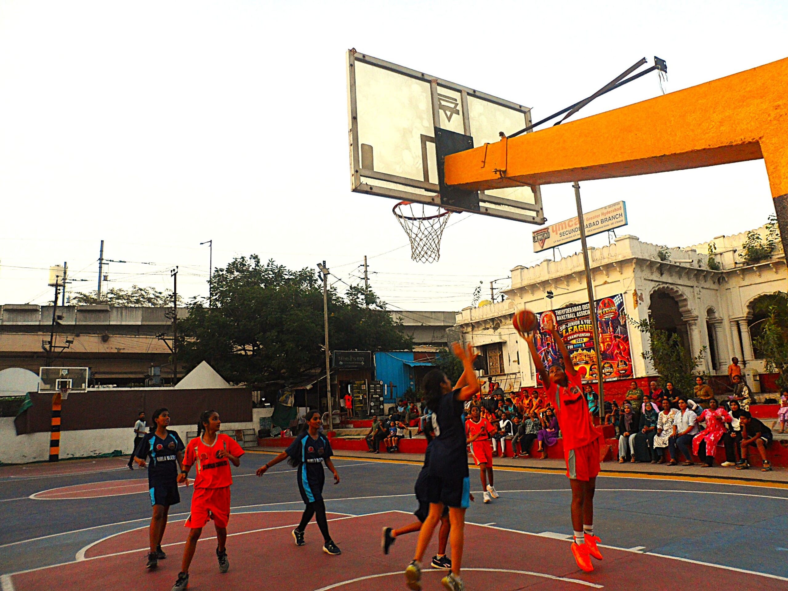 Aairah (Orange) of Charminar Chargers taking a shot as Pranavi (Blue) of Birla Blazers tries to block.